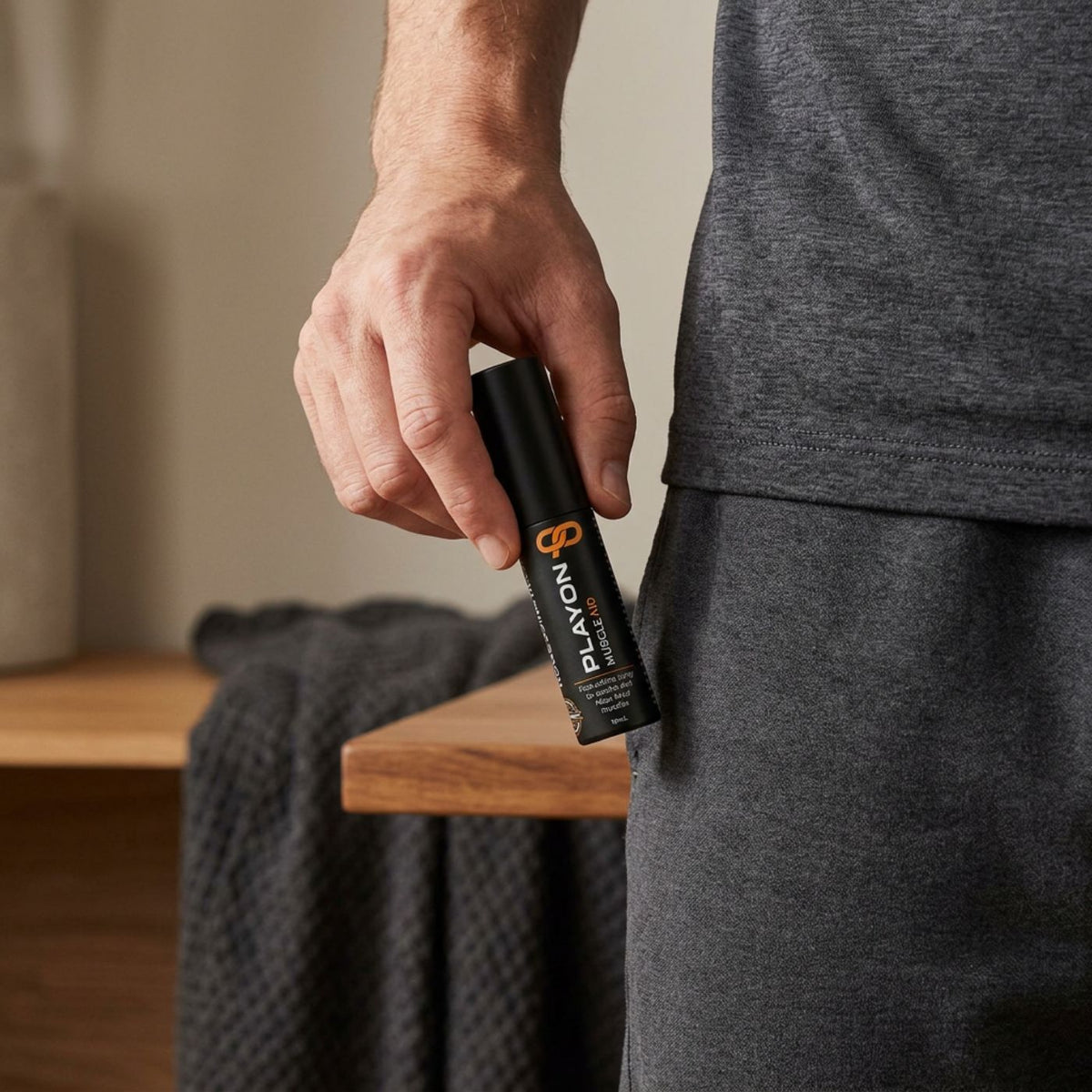 Adult holding a compact PLAYON Muscle Aid 10ml spray bottle